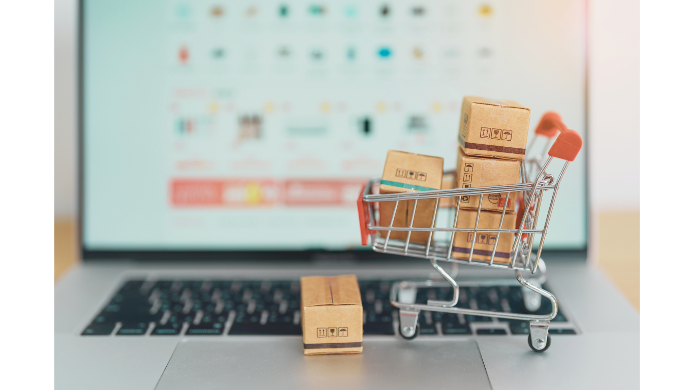 A mini shopping cart with boxes on a laptop, symbolizing online phone trade-ins as an alternative to eco ATMs